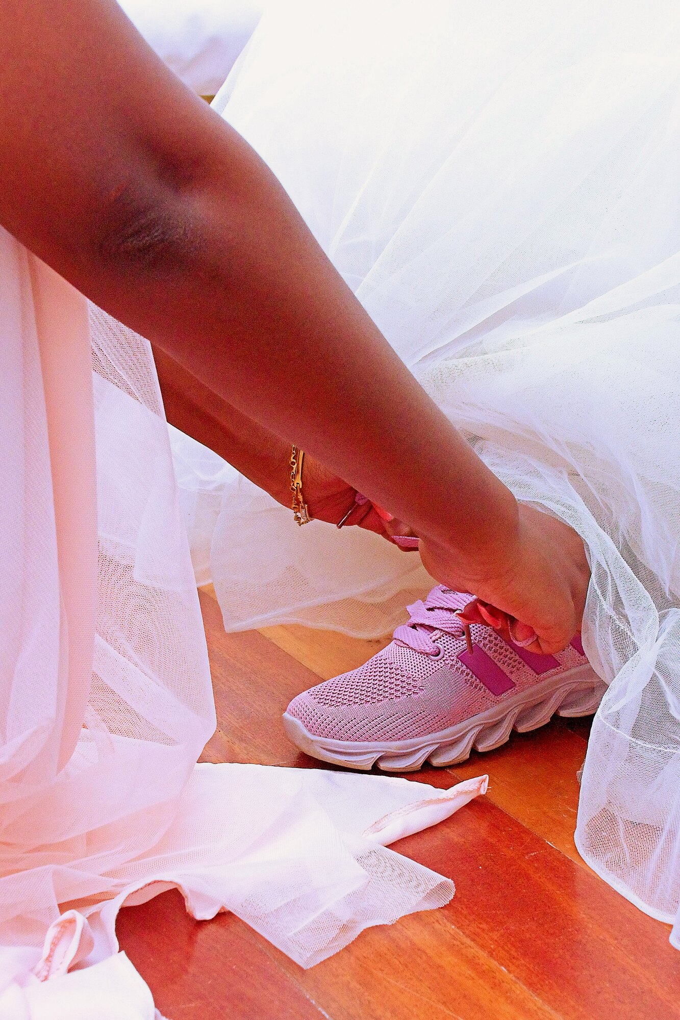 A bride ties her trainers beneath the layers of her wedding dress.