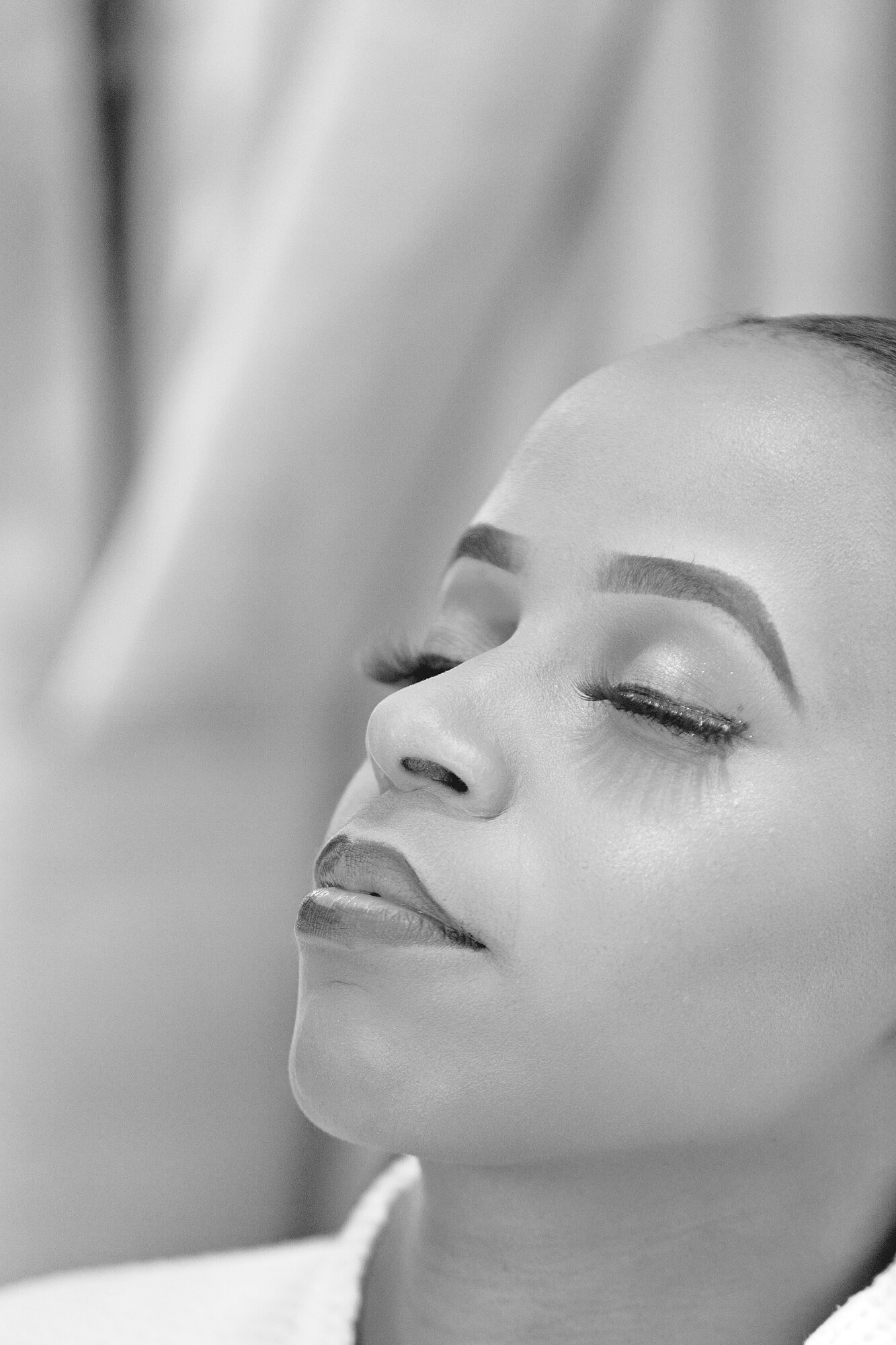 A black-and-white close portrait of a bride with her eyes closed.