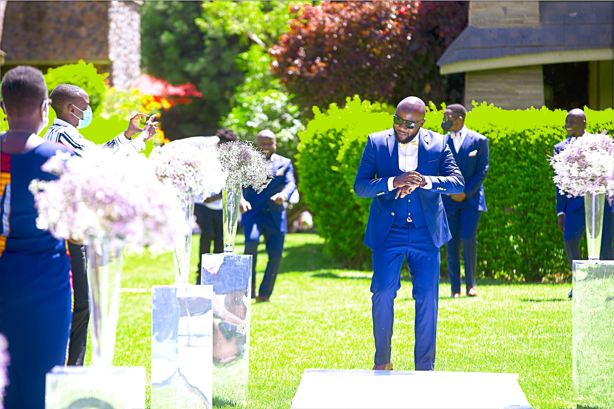 A groom stands at the front of an outdoor ceremony.