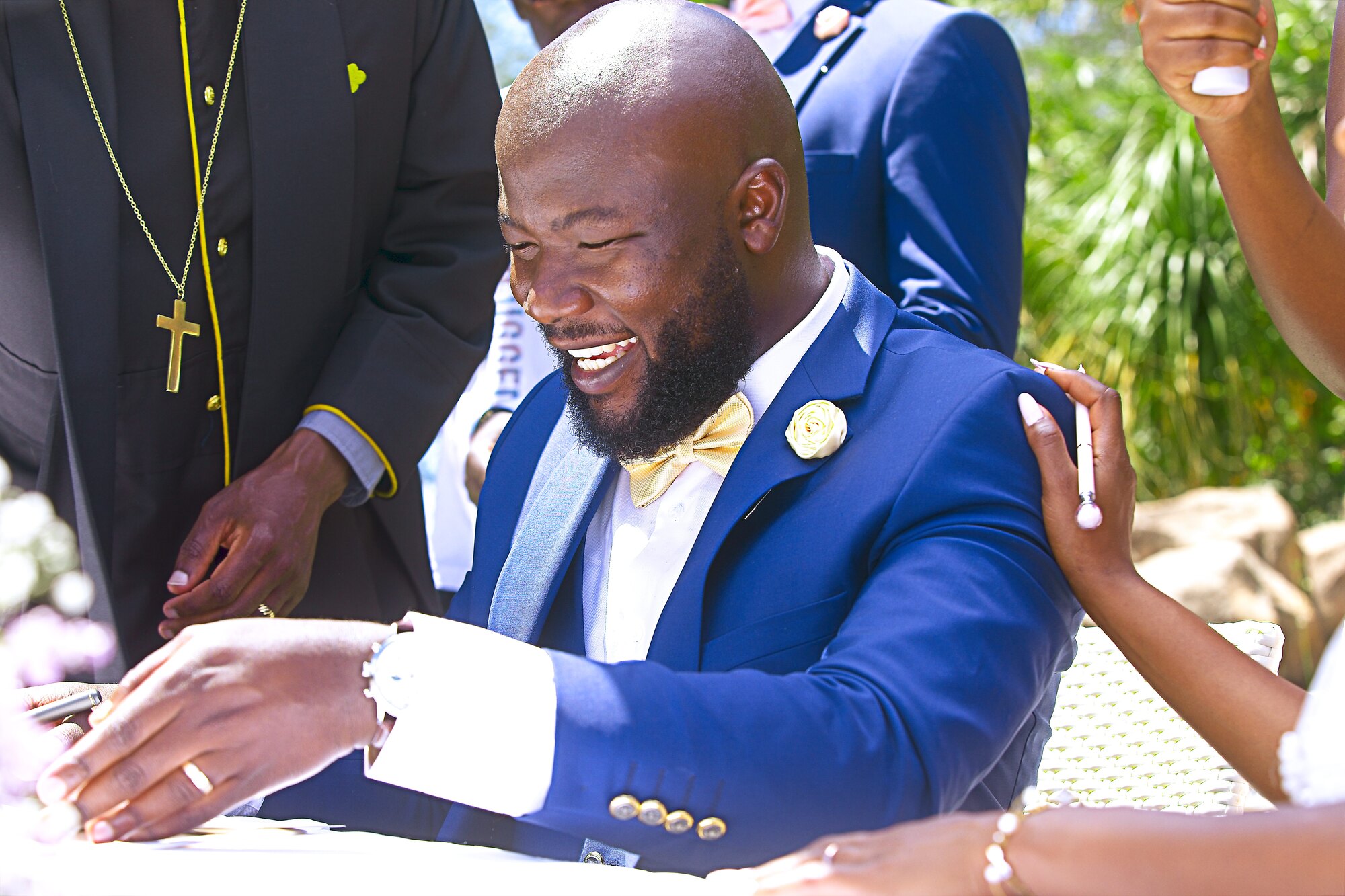 A groom laughs while seated at the ceremony table.